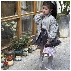 Girl wearing a purple checkered handbag with cute puppy charm and a silver shiny jacket