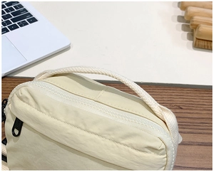 Detail view of cream canvas kids crossbody bag with woven handles and zipper