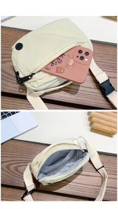 Close-up of off-white nylon crossbody bag with dual zippers and adjustable strap
