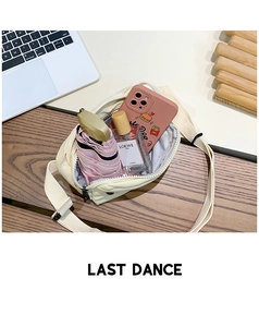 Internal storage detail of cream canvas crossbody bag with phone, perfume, and umbrella