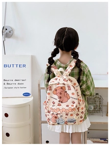 Rear view of girl wearing a cream canvas backpack with cute Capybara and orange prints