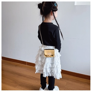 Close-up of golden heart-shaped mini shoulder bag with metallic chain on a child