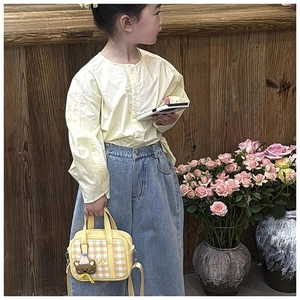 Detailed view of yellow plaid kids tote bag with cute bear charm on a casual outfit