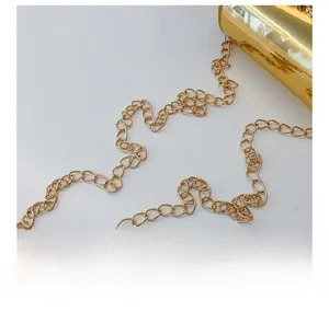 Détail de la bandoulière en chaîne dorée et de la surface brillante du sac pour filles