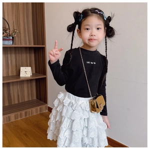 Girl wearing a black long sleeve shirt with layered white lace skirt and golden chain bag