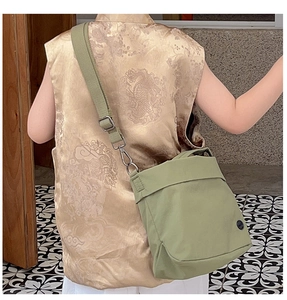 Detail of light green canvas shoulder bag with adjustable strap on a traditional vest