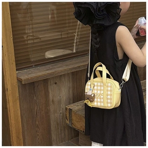 Detail of yellow checkered children's handbag with bear charm and adjustable strap