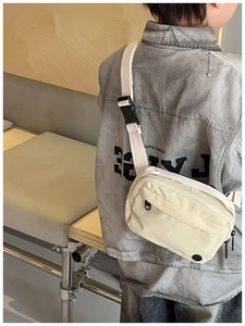 Detail view of cream canvas crossbody bag with adjustable strap and dual zipper compartments