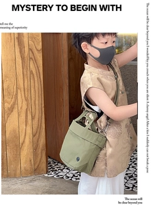 Detail view of olive green canvas bucket bag featuring top handle and metal hardware
