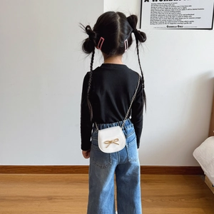 Borsa a tracolla bianca per bambina con fiocco dorato e catena indossata da bimba