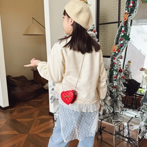 Girl wearing a heart-shaped red chain bag with lace top and denim tulle pants in a cozy room
