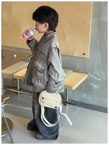 Detailed view of child wearing grey utility shirt with multi-pocket and white canvas cross-body bag