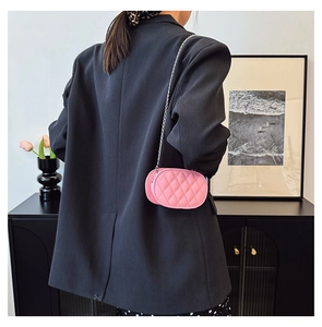 Pink quilted oval mini bag for kids with silver chain strap shown in home decor setting