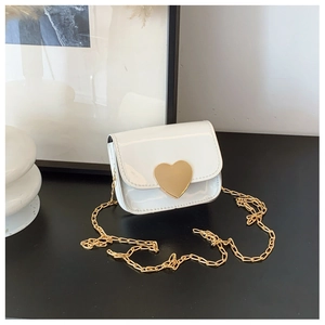 Detail of white patent leather mini bag featuring a large gold heart clasp and chain strap