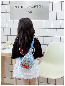 Detailansicht eines Kindes mit blau karierter Brusttasche und Capybara-Aufdruck