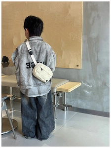 Detail of cream white canvas kids chest bag with adjustable strap and plastic buckle