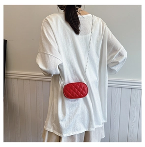 Rear view of a child wearing a red quilted oval crossbody bag with a silver chain strap