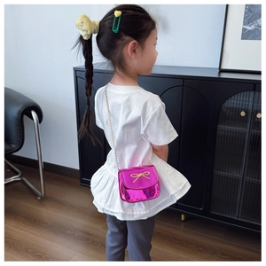 Détail du mini sac bandoulière rose fuchsia pour fille avec nœud doré et bandoulière chaîne