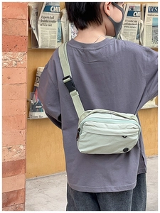 Detail of mint green nylon kids crossbody bag with black buckle and rubber logo patch