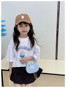Détail d'une tenue de mode enfant avec sac à chaîne bleu et t-shirt blanc graphique