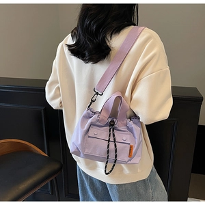 Détail du sac seau en toile violette avec cordon de serrage et étiquette de marque orange