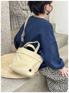 Detail showing beige canvas kids crossbody bag with adjustable strap and logo patch