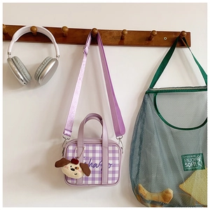 Detail of purple plaid mini kids bag with dog plush charm hanging on a hanger