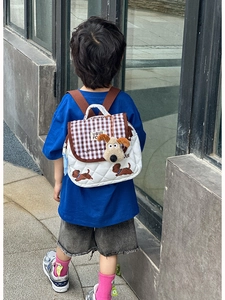 Close-up of quilted kids backpack with puppy print and cute plush dog charm detail
