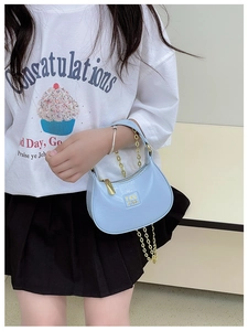 Détail du mini sac croissant bleu clair avec chaîne dorée et logo en métal