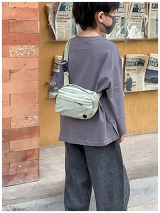 Detail of mint green canvas kids crossbody bag with adjustable strap and buckle on model