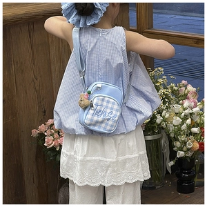 Detail of light blue checkered children's crossbody bag with brown bear charm