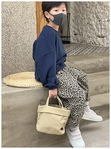 Close-up of a child holding a minimalist beige canvas tote bag on concrete steps