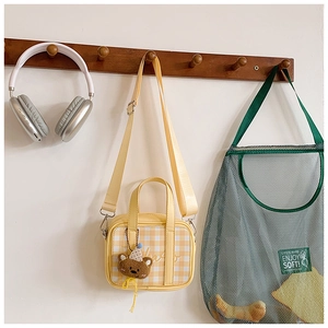 Detail of yellow checkered mini tote bag with cute bear pendant and nylon shoulder strap
