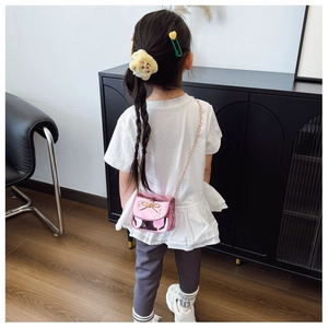 Détail du mini sac rose brillant avec nœud doré et bandoulière en chaîne métallique