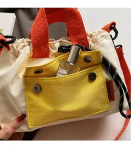 Détail du sac seau en toile avec sangles oranges, cordon de serrage et poche avant jaune