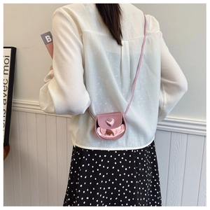 Girl wearing a mini pink heart-shaped crossbody bag with glossy metallic finish