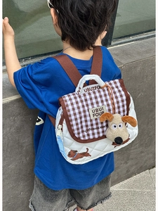 Detail of white quilted children backpack with cute dog charm and brown checkered flap