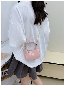 Détail d'un sac demi-lune rose en similicuir avec bandoulière chaîne sur modèle