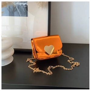 Close-up of orange metallic mini bag with large gold heart buckle and chain strap