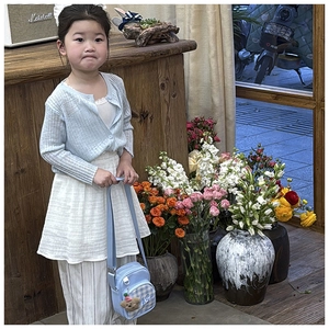 Detail of cute blue plaid crossbody bag styled with a children knitted cardigan and outfit