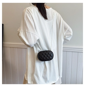 Kids quilted black oval crossbody bag with silver chain strap shown on a model