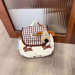Close-up of quilted cream backpack with brown plaid flap and cute plush dog pendant
