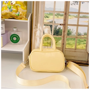 Close-up of bright yellow PU leather mini bag with wide nylon strap and silver hardware