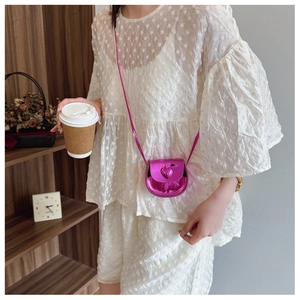 Detailed view of mini metallic rose red heart bag worn on model with chain strap