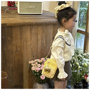 Close-up of a yellow kids crossbody bag with 3D cartoon bear and plaid pocket detail