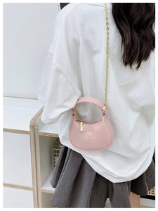 Détail du mini sac demi-lune rose avec bandoulière chaîne dorée sur mannequin