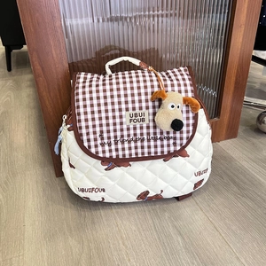 Detail of quilted kids backpack featuring brown puppy print and cute plush charm