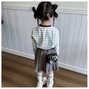 Vue arrière d'une fille portant un sac bandoulière en cuir verni noir avec nœud doré