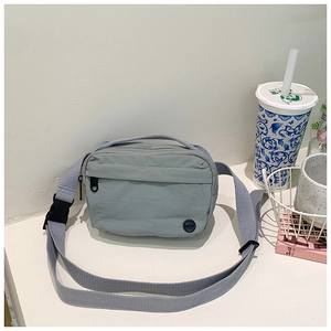Detail of grey-blue nylon crossbody bag with zipper pockets and adjustable strap
