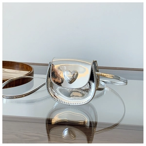 Detailed view of a silver heart-shaped accent on a metallic mirror finish crossbody bag